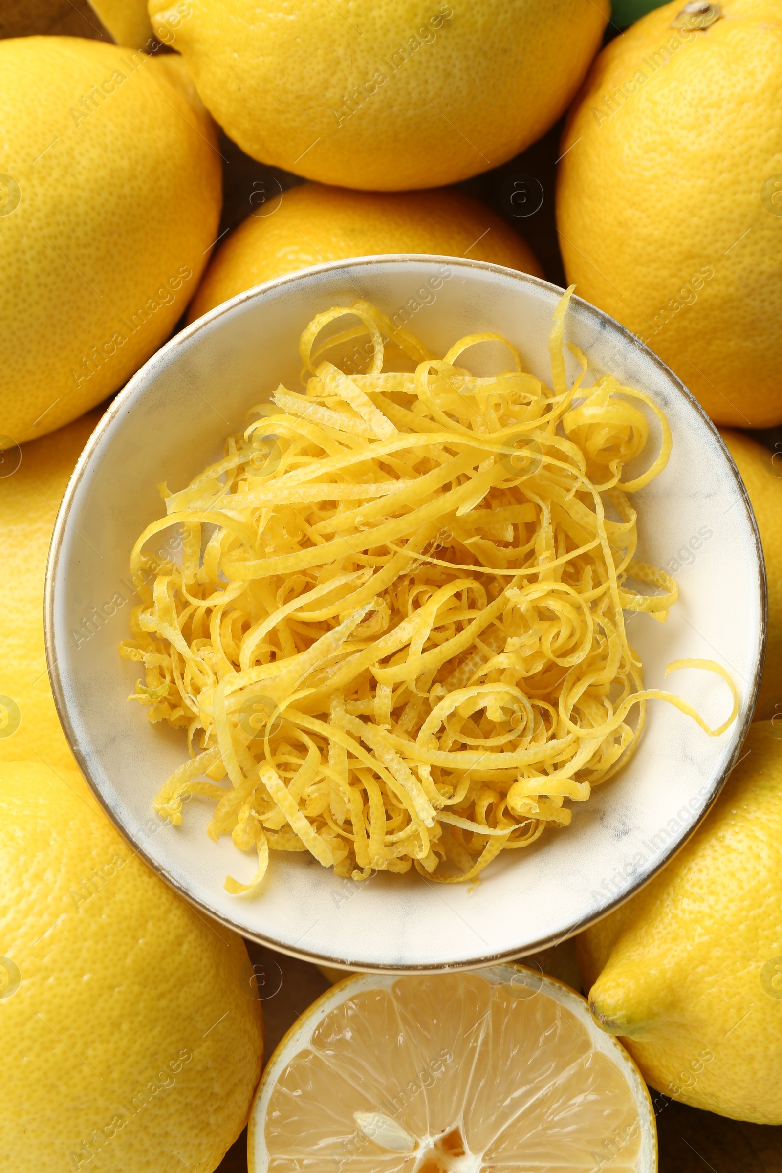 Photo of Lemon zest in bowl on fresh fruits, closeup