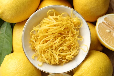 Photo of Lemon zest in bowl on fresh fruits, closeup