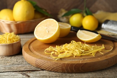 Photo of Lemon zest, tools and fresh fruits on wooden table, closeup