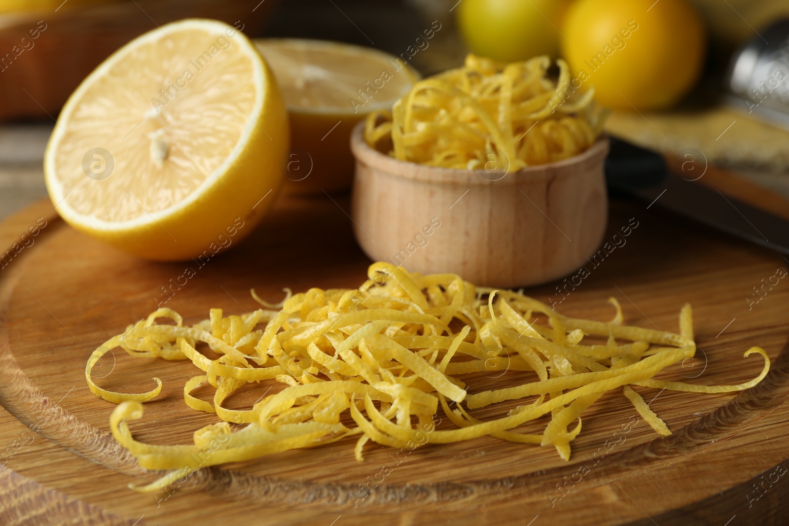 Photo of Lemon zest, knife and fresh fruits on wooden table, closeup