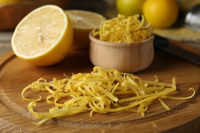 Photo of Lemon zest, knife and fresh fruits on wooden table, closeup