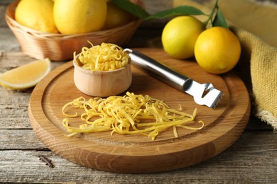 Photo of Lemon zest, zester tool and fresh fruits on wooden table, closeup