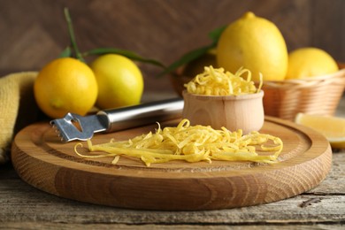 Photo of Lemon zest, zester tool and fresh fruits on wooden table, closeup