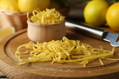 Photo of Lemon zest, zester tool and fresh fruits on wooden table, closeup