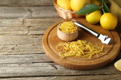 Photo of Lemon zest, zester tool and fresh fruits on wooden table, closeup