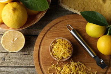 Photo of Lemon zest, zester tool and fresh fruits on wooden table, flat lay