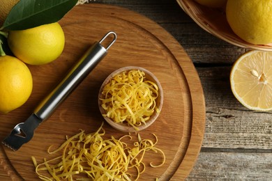 Photo of Lemon zest, zester tool and fresh fruits on wooden table, flat lay