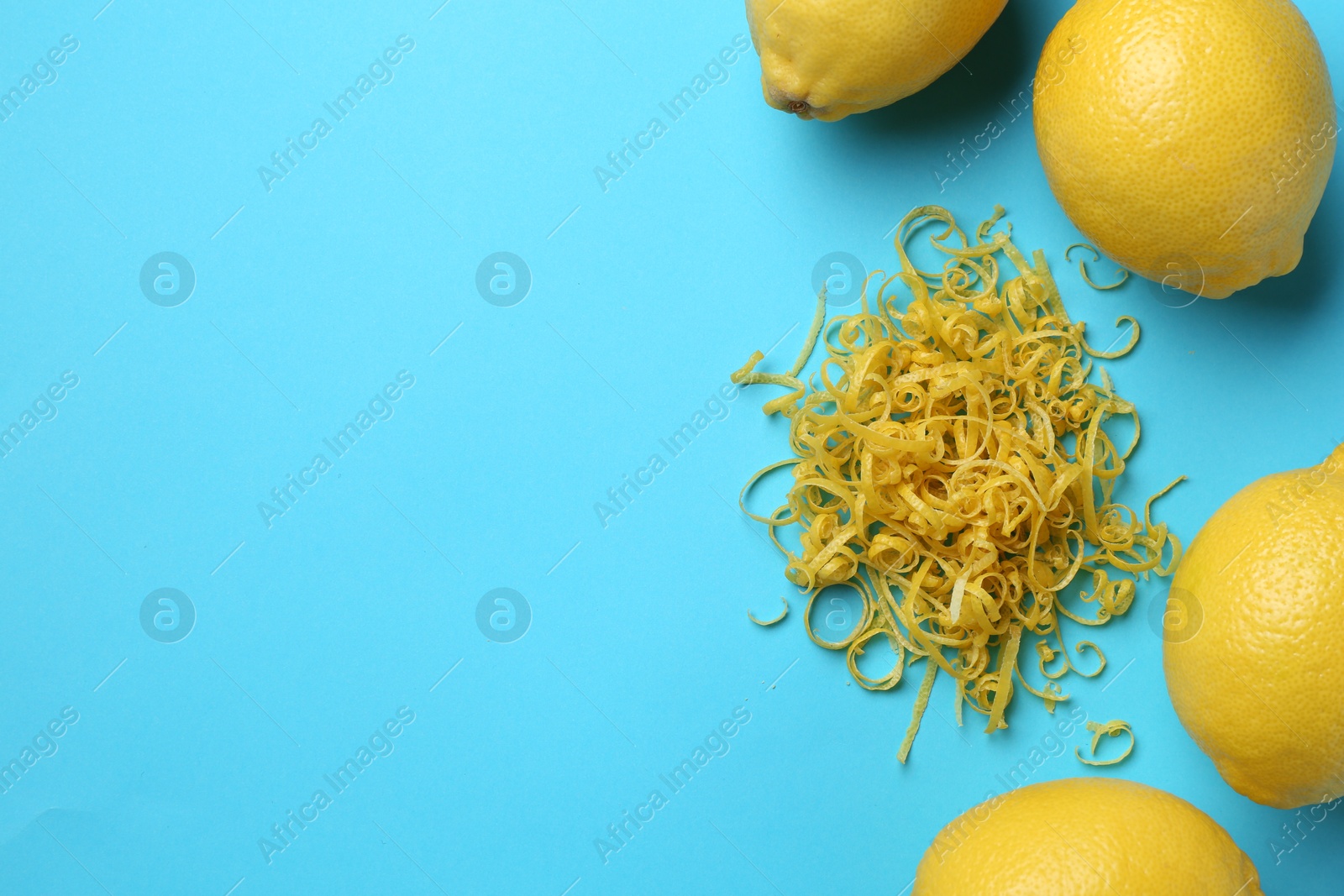 Photo of Lemon zest and fresh fruits on light blue background, flat lay. Space for text