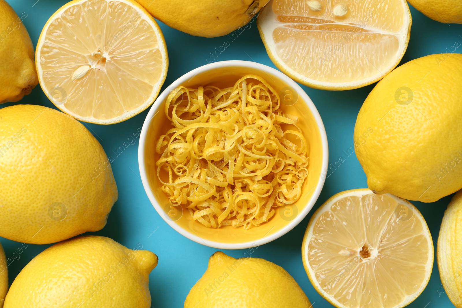 Photo of Lemon zest in bowl and fresh fruits on light blue background, top view