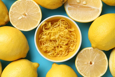 Photo of Lemon zest in bowl and fresh fruits on light blue background, top view