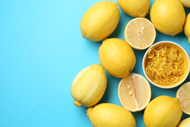 Photo of Lemon zest in bowl and fresh fruits on light blue background, top view. Space for text