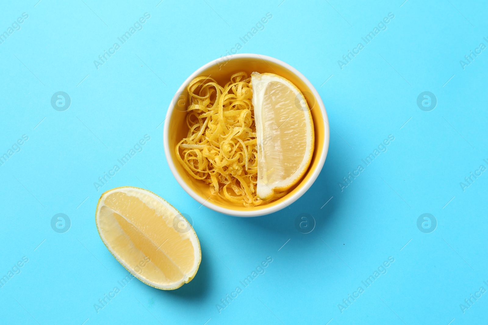 Photo of Lemon zest and pieces of fresh fruit on light blue background, top view