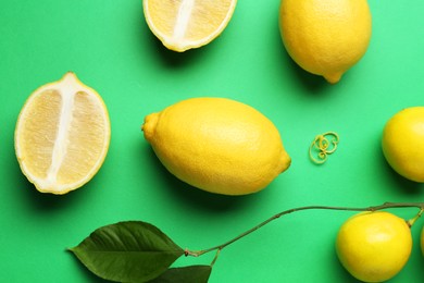 Photo of Lemon zest, fresh fruits and leaves on green background, flat lay