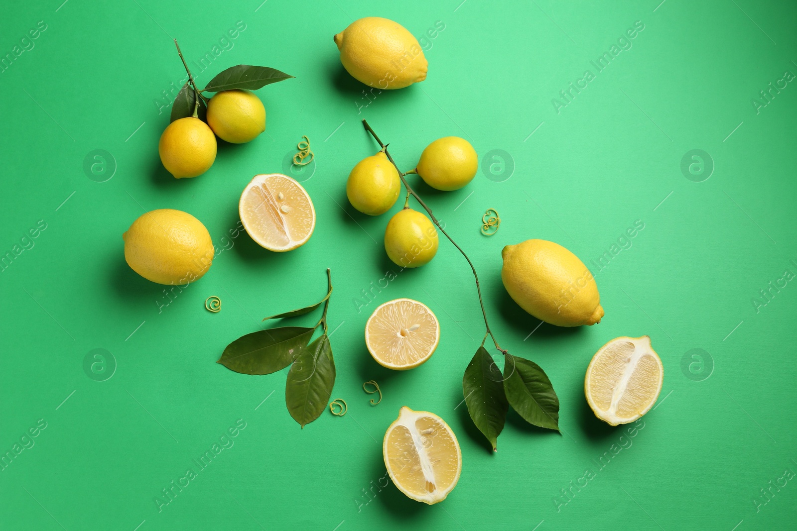 Photo of Lemon zest, fresh fruits and leaves on green background, flat lay