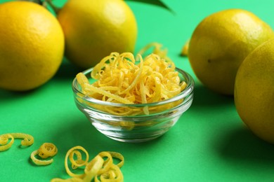 Photo of Lemon zest and fresh fruits on green background, closeup