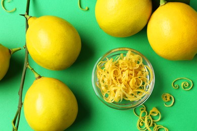 Photo of Lemon zest and fresh fruits on green background, flat lay