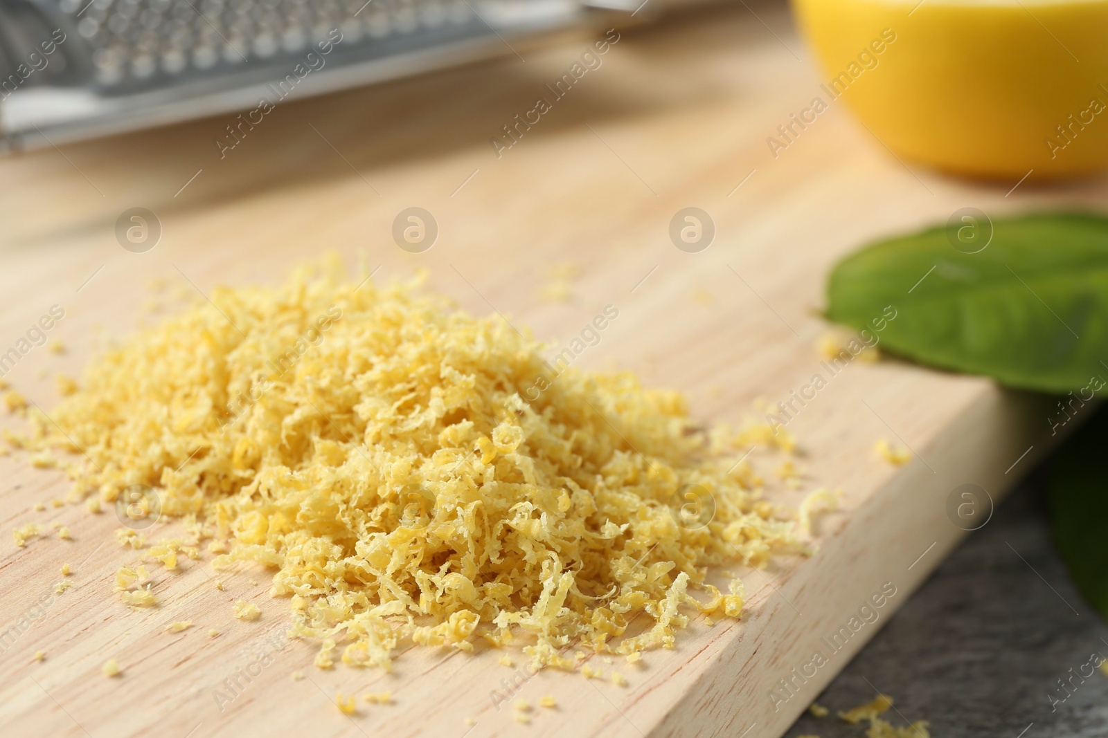 Photo of Wooden board with lemon zest on grey table, closeup