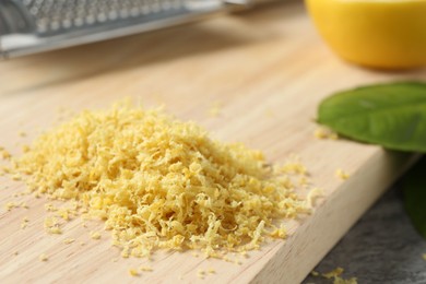 Photo of Wooden board with lemon zest on grey table, closeup