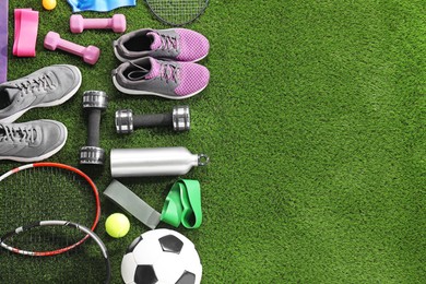 Photo of Different sport equipment on artificial grass, flat lay. Space for text