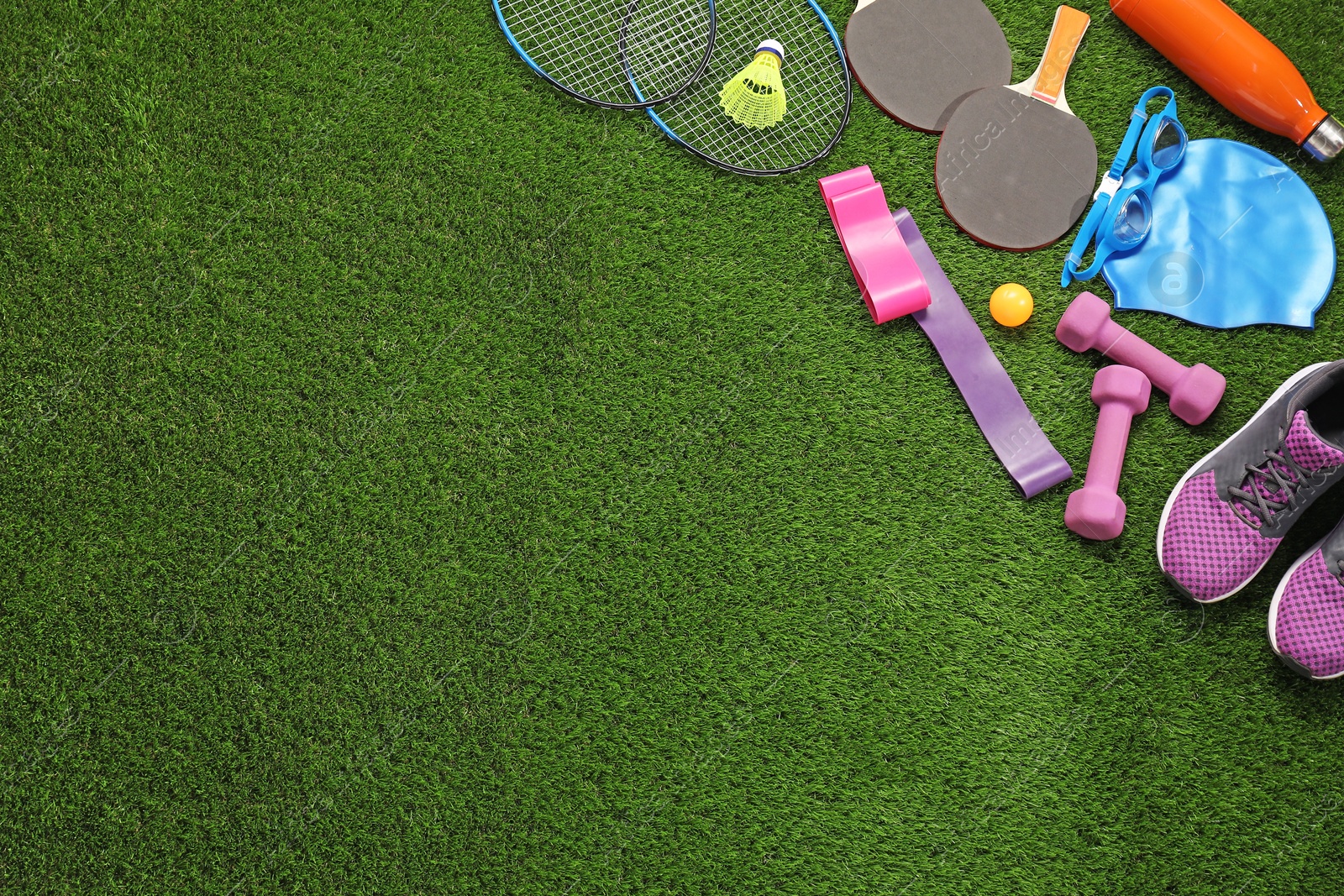 Photo of Different sport equipment on artificial grass, flat lay. Space for text