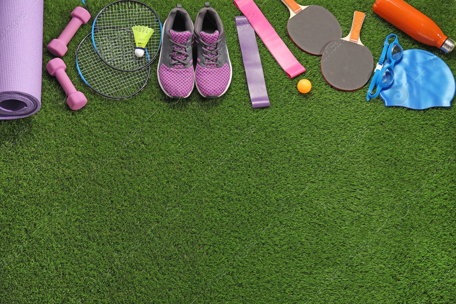 Photo of Different sport equipment on artificial grass, flat lay. Space for text