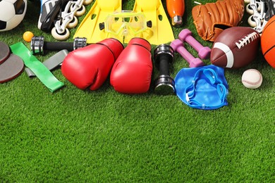 Photo of Different sport equipment on artificial grass, above view. Space for text