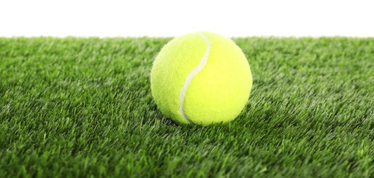 Photo of Tennis ball on artificial grass isolated on white. Sport equipment