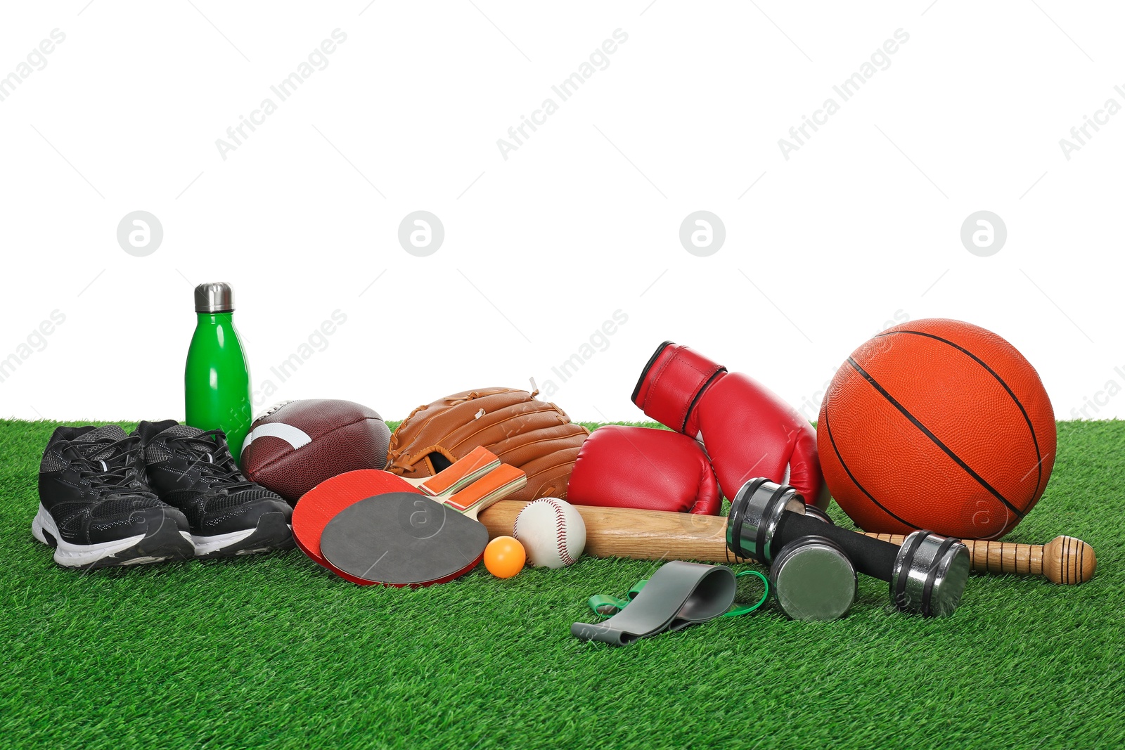 Photo of Different sport equipment on green grass against white background