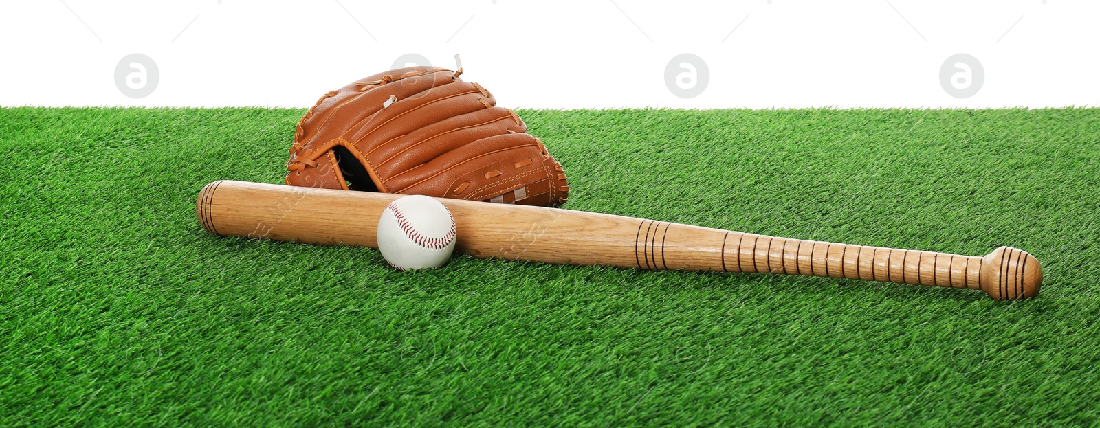 Photo of Baseball bat, ball and glove on green grass against white background. Sport equipment