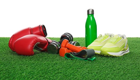 Photo of Different sport equipment on green grass against white background