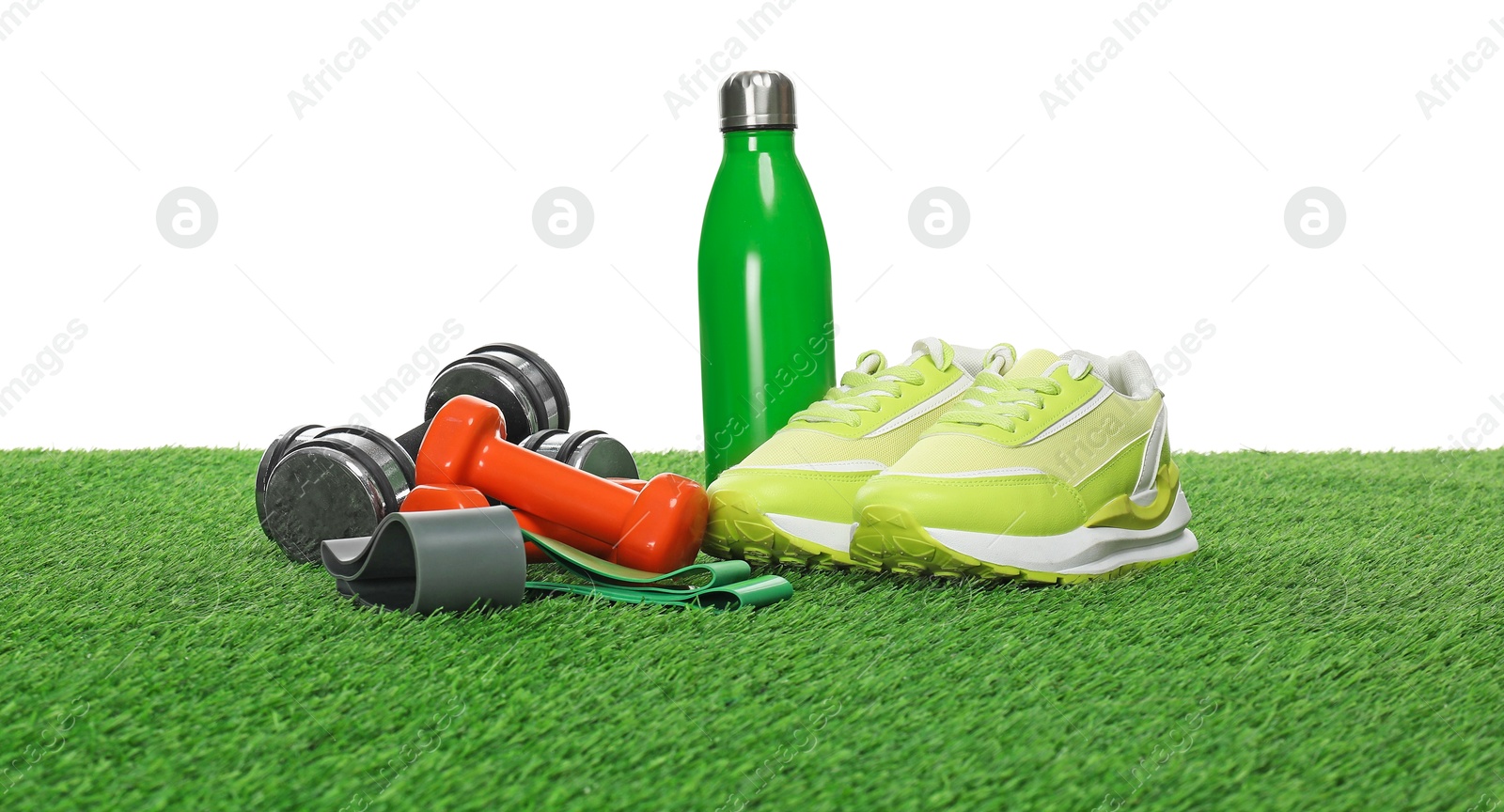 Photo of Different sport equipment on green grass against white background