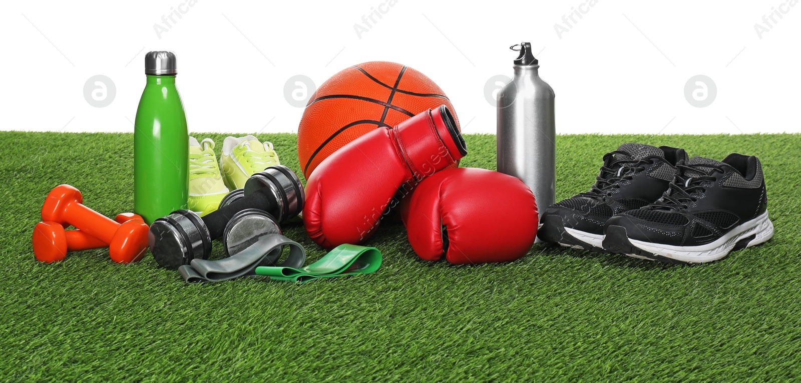 Photo of Different sport equipment on green grass against white background