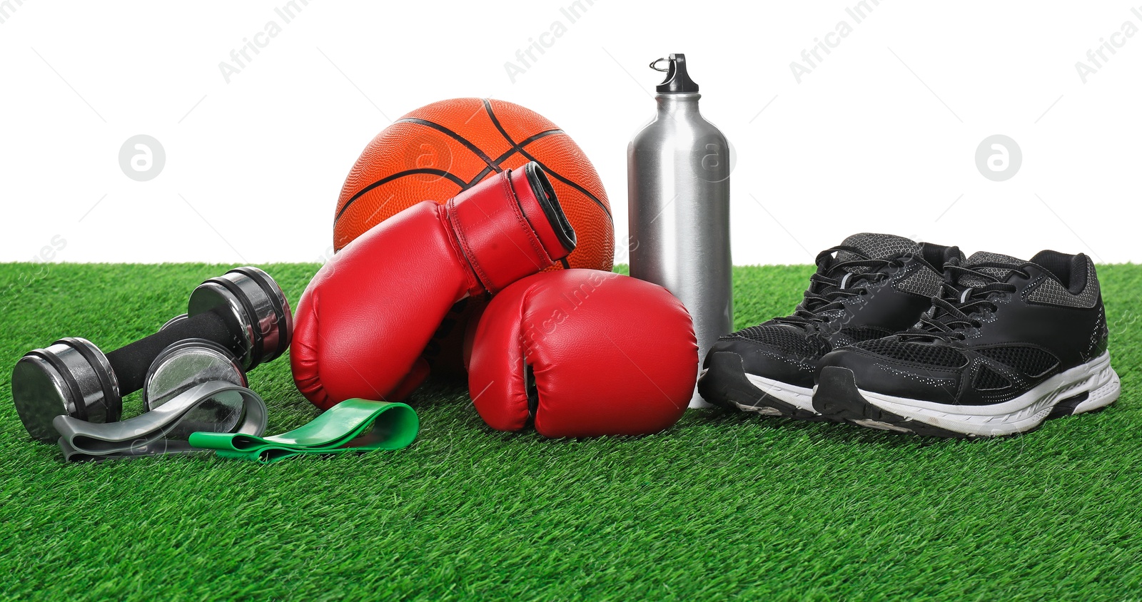 Photo of Different sport equipment on green grass against white background