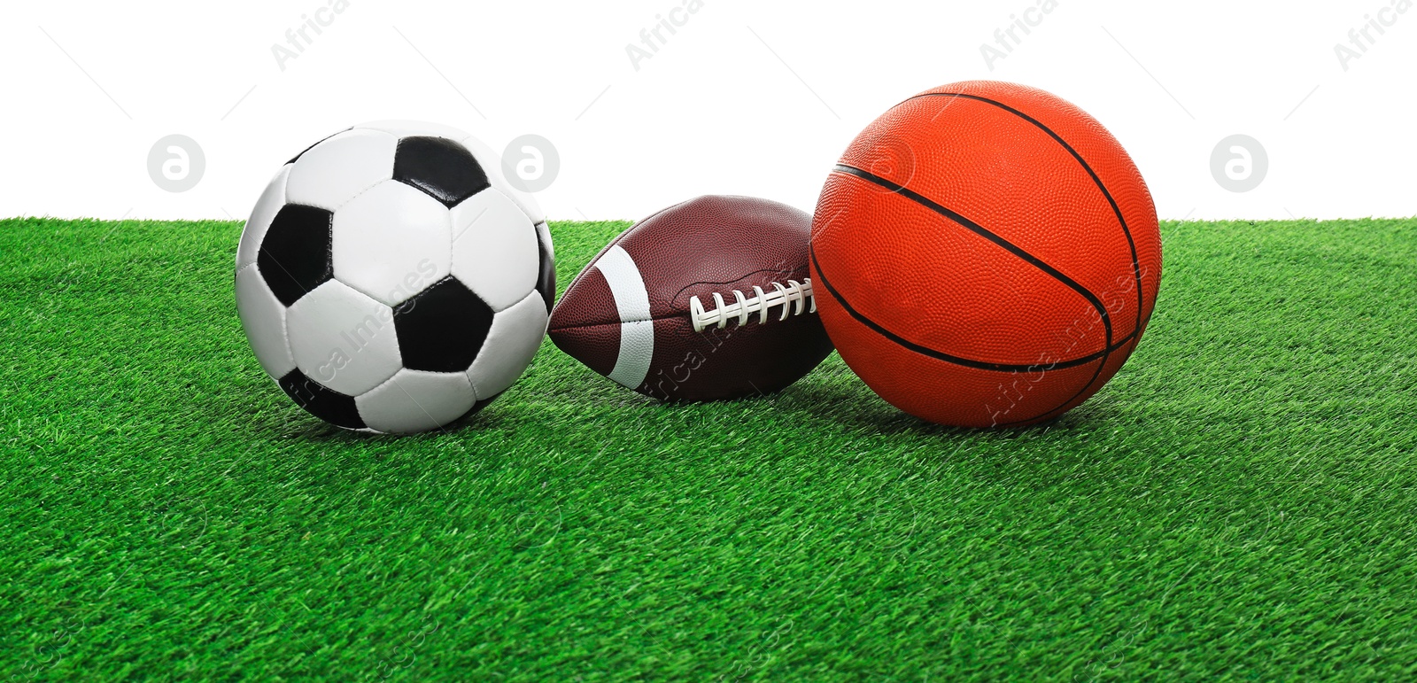 Photo of Different balls on artificial grass against white background. Sport equipment