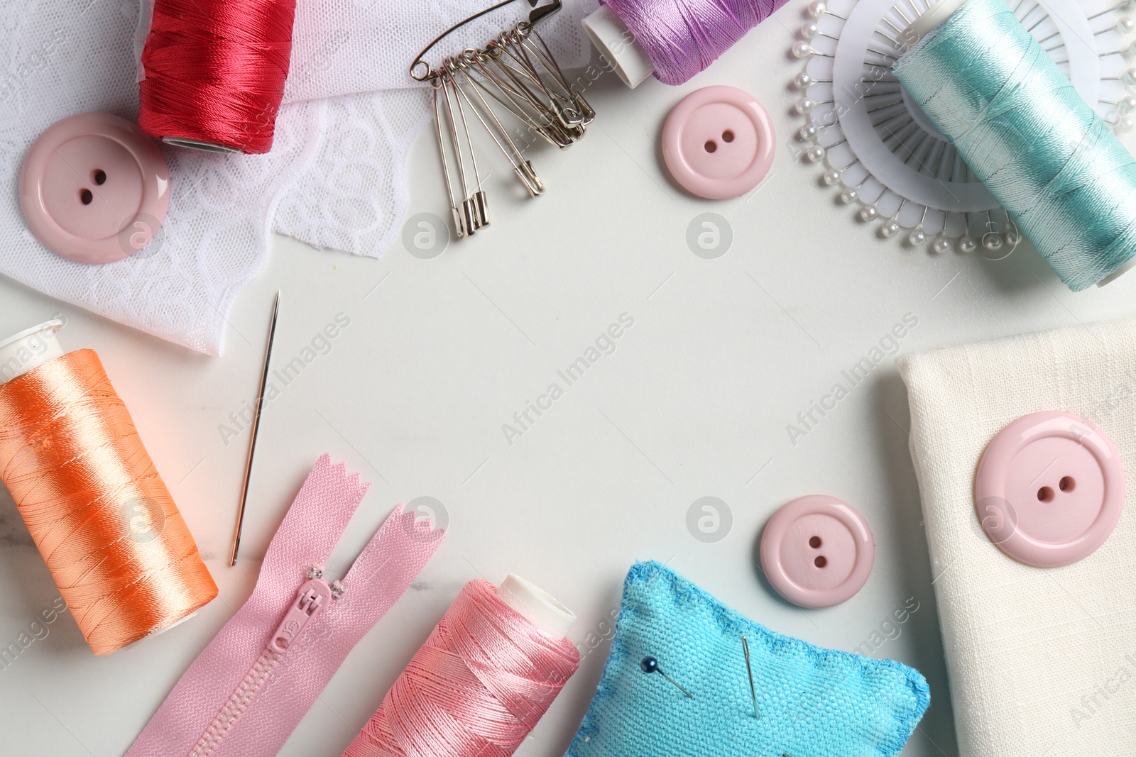 Photo of Frame made of different sewing supplies on white marble table, flat lay. Space for text