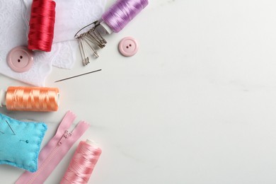 Photo of Different sewing supplies on white marble table, flat lay. Space for text