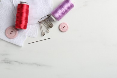 Photo of Different sewing supplies on white marble table, flat lay. Space for text