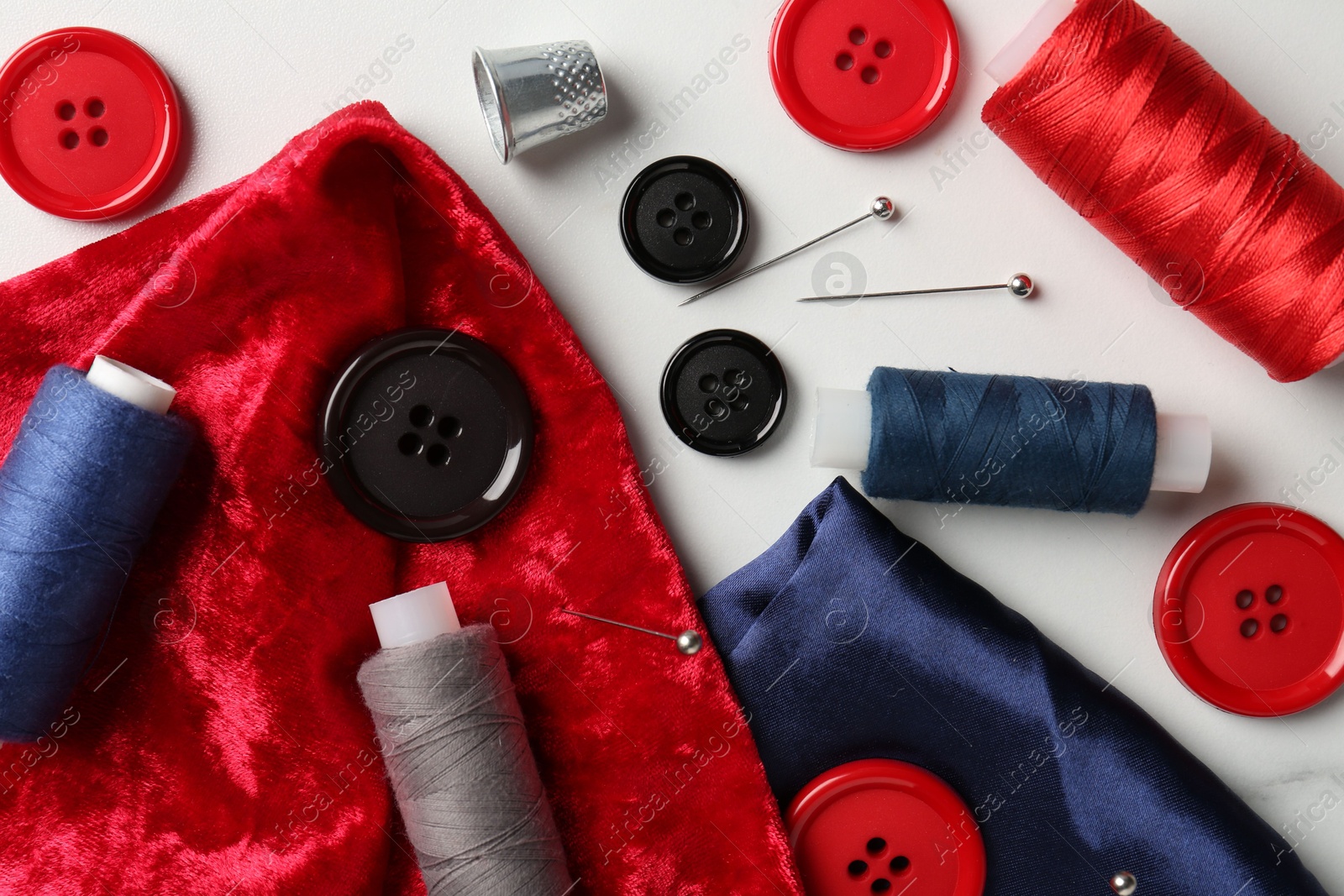 Photo of Different sewing supplies on white marble table, flat lay