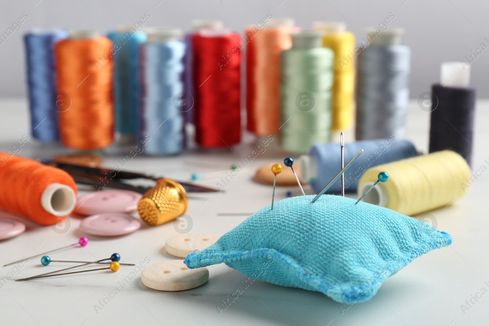 Photo of Different sewing supplies on white marble table, closeup