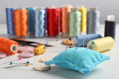 Photo of Different sewing supplies on white marble table, closeup