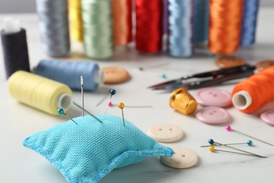 Photo of Different sewing supplies on white marble table, closeup