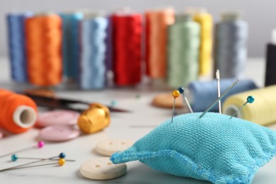 Photo of Different sewing supplies on white marble table, closeup