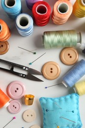 Photo of Different sewing supplies on white marble table, flat lay