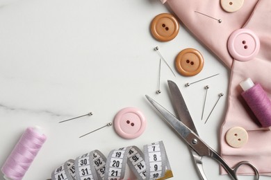 Photo of Different sewing supplies on white marble table, flat lay. Space for text