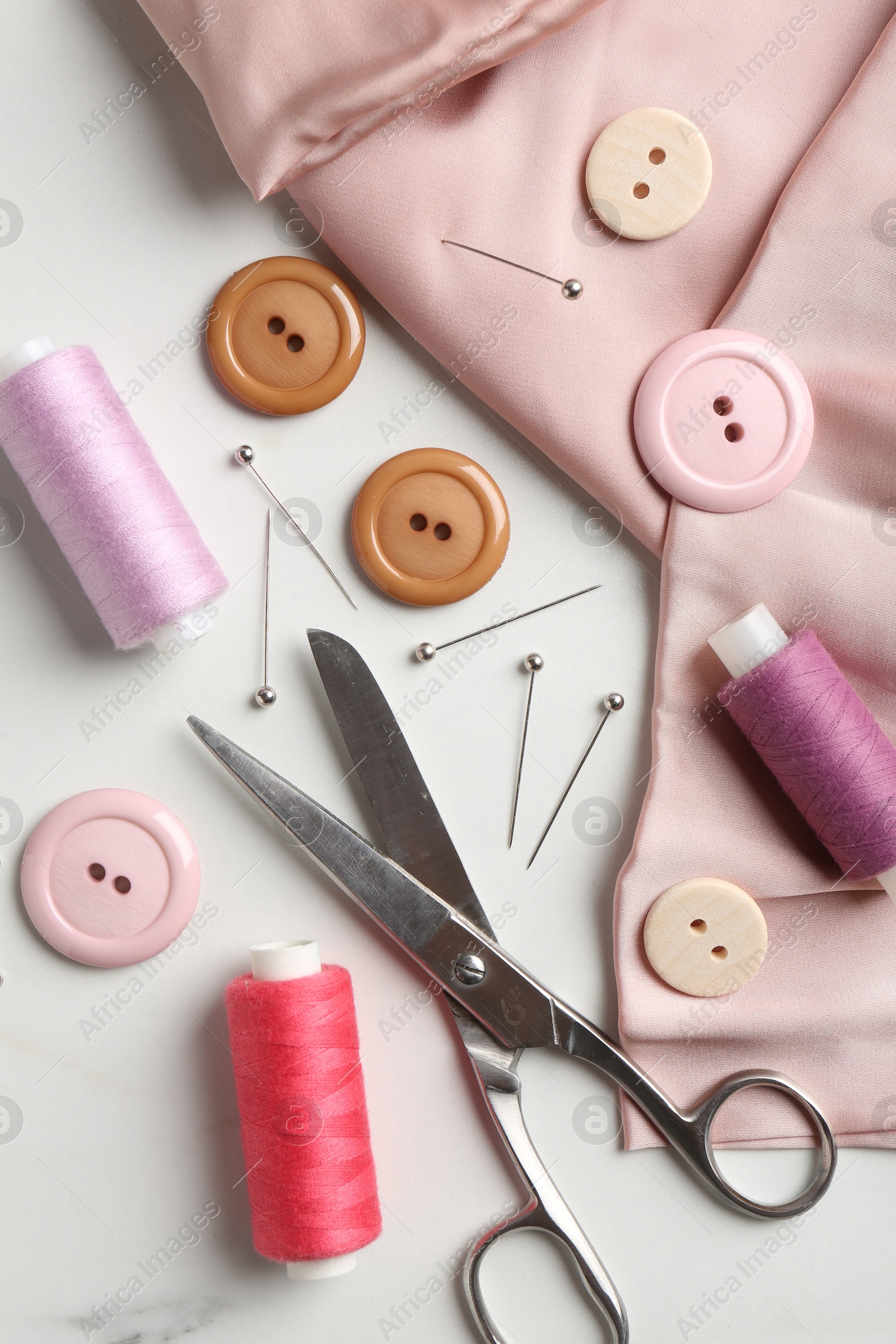 Photo of Different sewing supplies on white marble table, flat lay