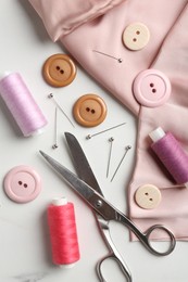 Photo of Different sewing supplies on white marble table, flat lay