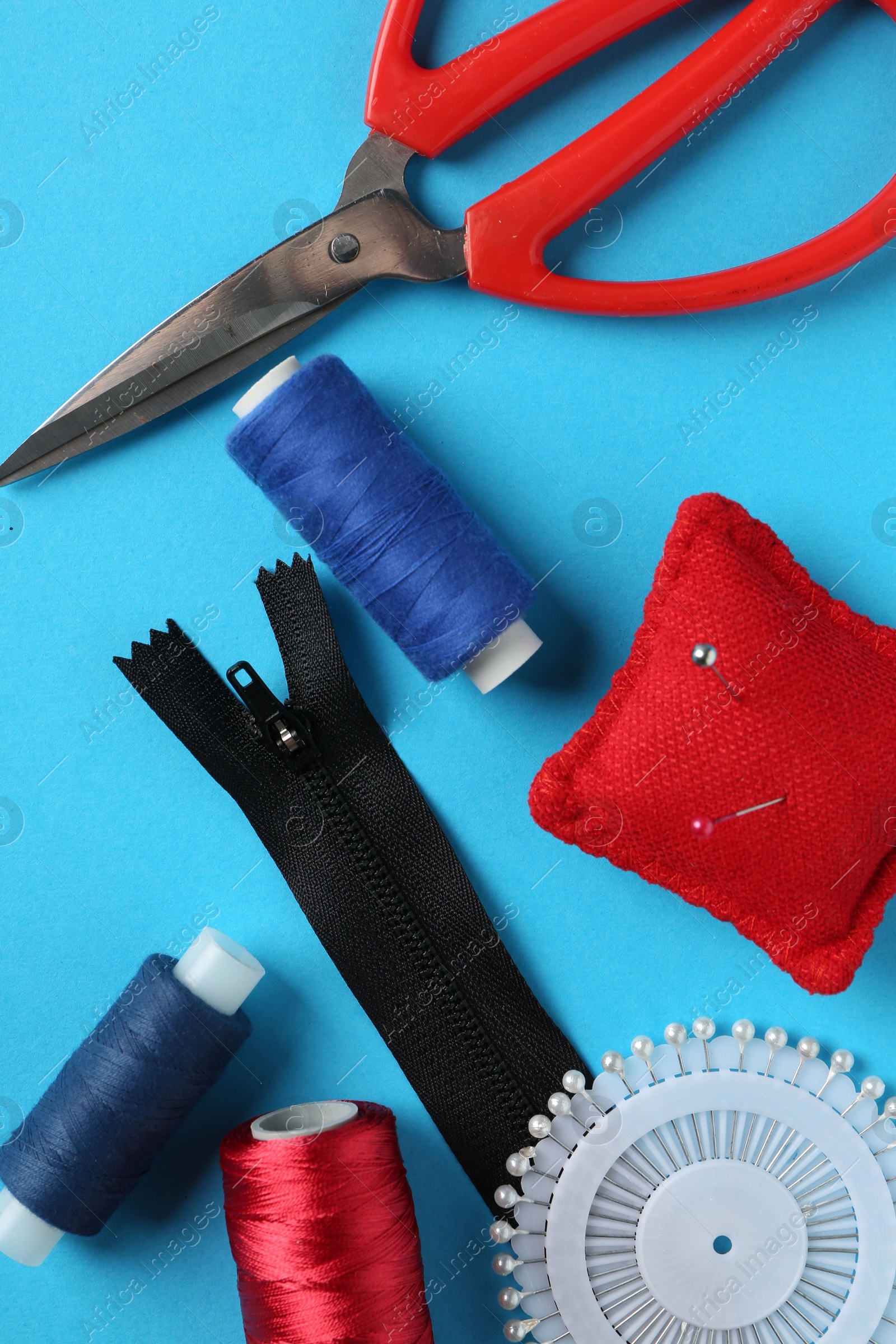 Photo of Different sewing supplies on light blue background, flat lay