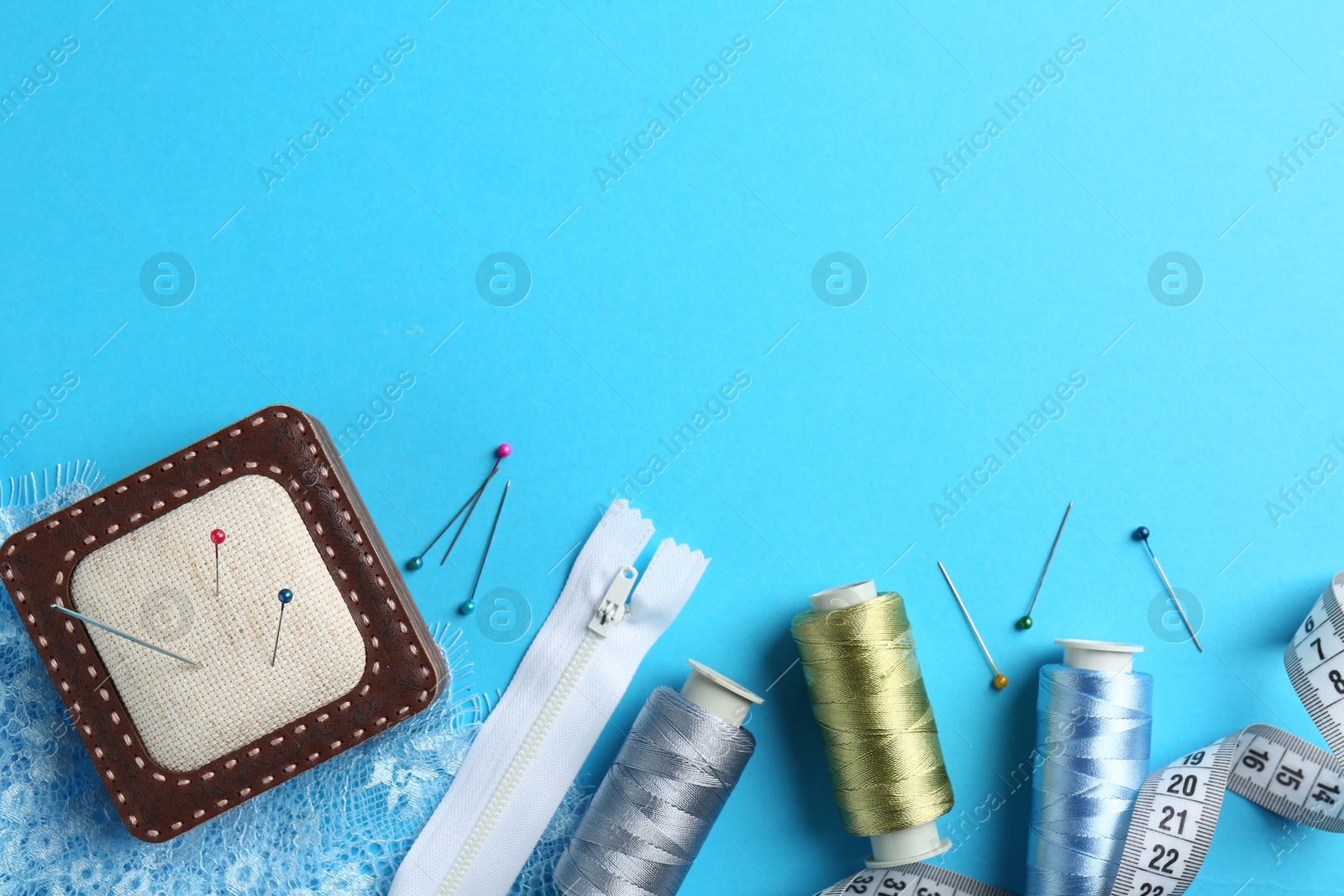 Photo of Different sewing supplies on light blue background, flat lay. Space for text