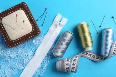 Photo of Different sewing supplies on light blue background, flat lay