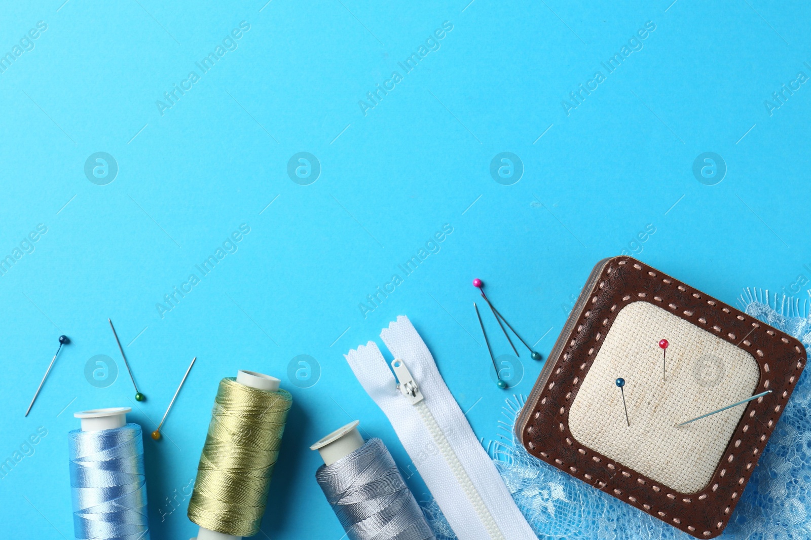 Photo of Different sewing supplies on light blue background, flat lay. Space for text